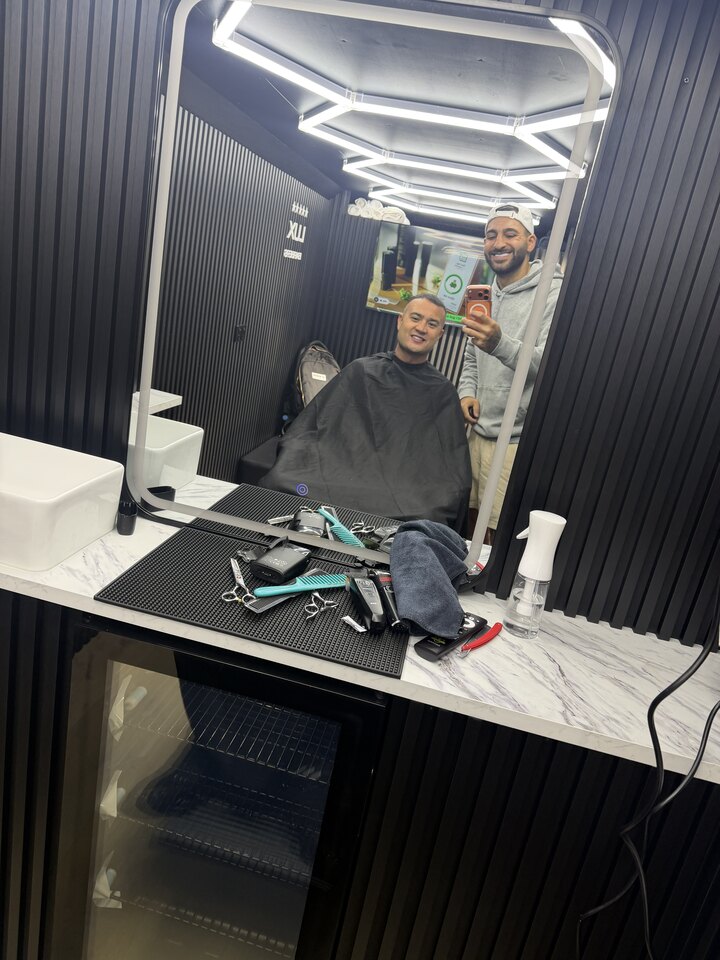 Ahmed, founder of Lux Barbers, in his mobile studio with a client