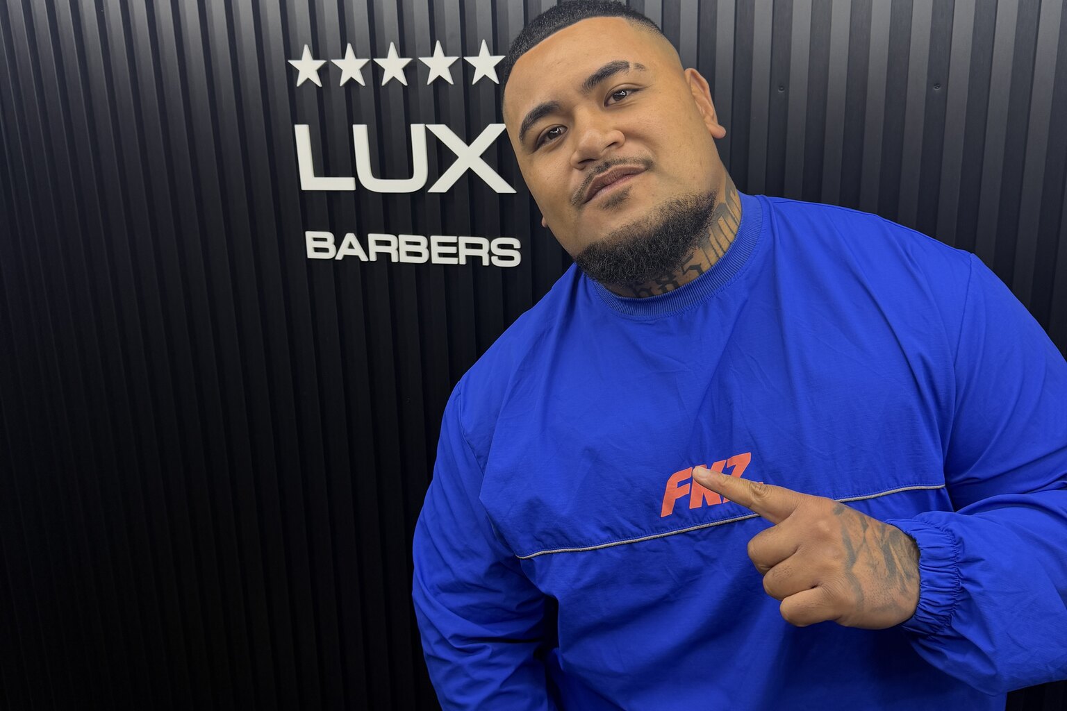 A happy Lux Barbers client by the studio signage